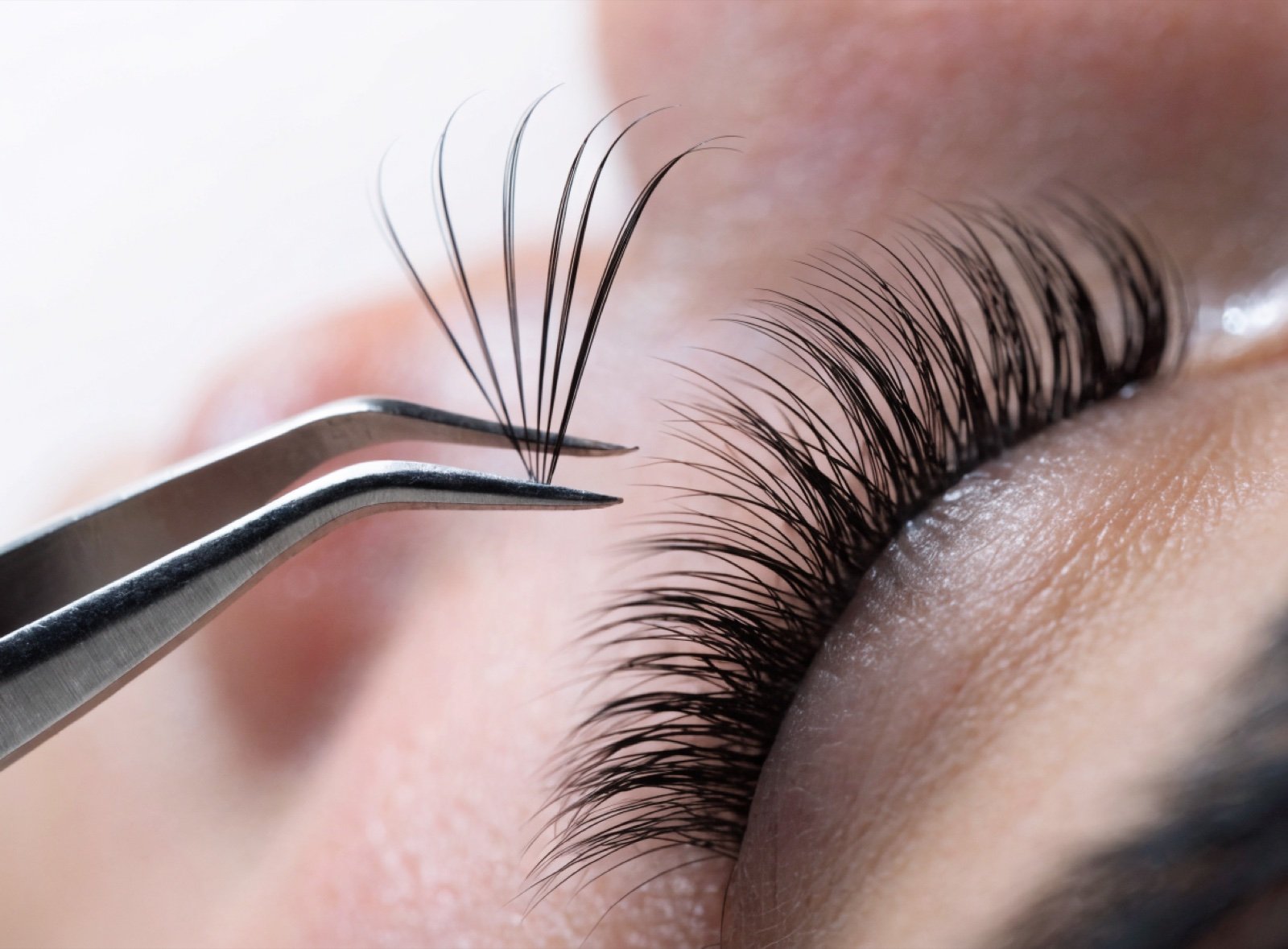 Eyelash extensions being applied with tweezers